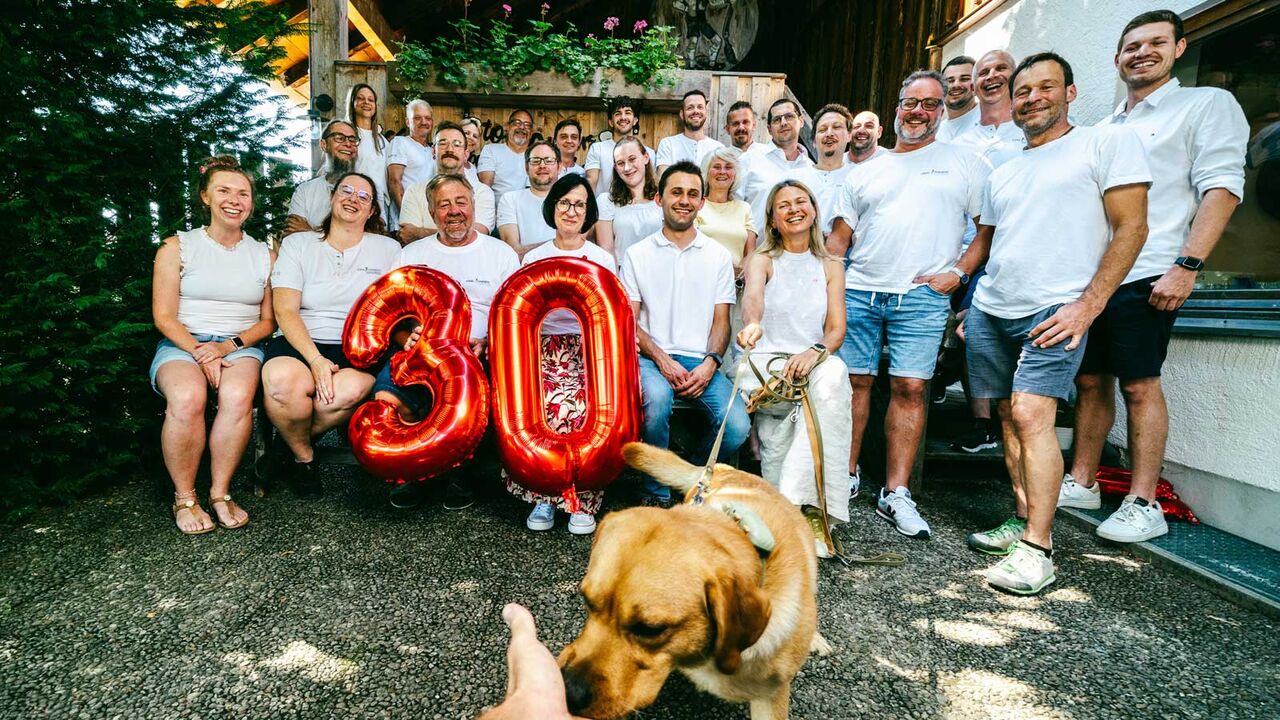 Gruppenfoto des Teams mit Ballonzahl 30 und Bürohund beim Firmenjubiläum